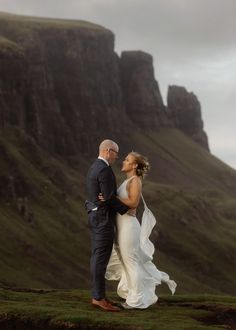 a bride and groom standing in front of a mountain