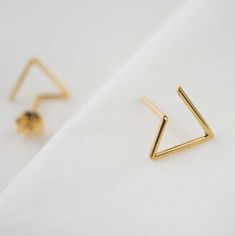 "Delicate triangle studs inspired by geometry and clean lines. These minimalist easy-to-wear earrings are simple but elegant, perfect choice to add a unique touch to your casual look. The pair of earrings is carefully handcrafted by us from a 1mm wire. Available in sterling silver or 22K yellow gold fill over sterling silver (5 micrometers of gold) both in shiny polished finish. Post of 19 gauge wire // 1mm diameter This listing is for one pair of earrings including ear backs. ------ HIGH QUALIT Triangle Studs, Minimalist Studs, Geometric Earrings, Recycled Sterling Silver, Gold Plated Silver, 22k Gold, Minimalist Earrings, Precious Metals, Geometry