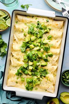 an enchilada dish with avocado and cilantro on the side