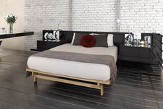 a bed sitting on top of a wooden floor next to a white brick wall