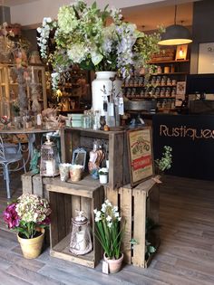 a flower shop with lots of flowers in the window and on top of wooden crates