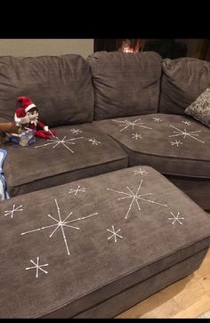 a cat sitting on top of a couch with snowflakes painted on the cushions