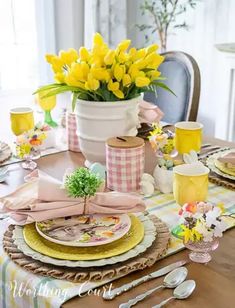 the table is set with yellow flowers and pink napkins, silverware, and utensils