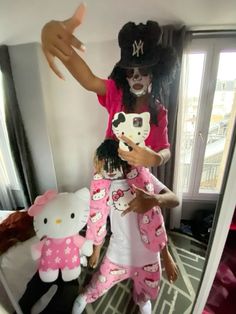 a woman in hello kitty pajamas is holding onto a stuffed animal and pointing at it