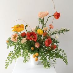 a white vase filled with lots of different colored flowers