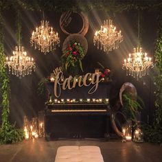 a piano sitting in front of a chandelier filled with candles and greenery