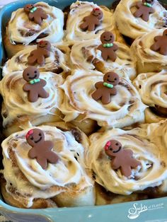 a blue dish filled with cinnamon rolls covered in icing and gingerbread men on top