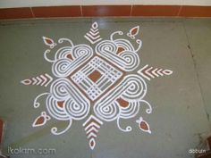 an intricate design is painted on the ground in white and brown colors with red accents