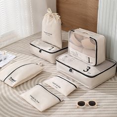 three pieces of luggage sitting on top of a bed next to sunglasses and a bag