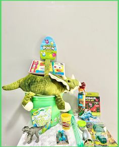 a stuffed animal sitting on top of a green bucket filled with toys and other items