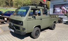 an army green truck parked in front of a building with people sitting on the bench