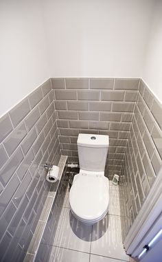 a white toilet sitting in a bathroom next to a radiator and tiled walls