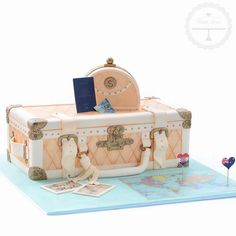 a cake made to look like an old fashioned trunk with luggage on top and decorations around it