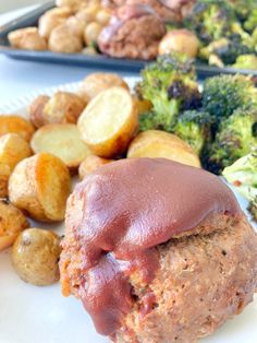 meatloaf, potatoes and broccoli on a white plate with red sauce