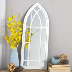 a vase with yellow flowers sitting next to a mirror