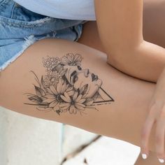 a woman's thigh with flowers and a triangle tattoo on her left side leg