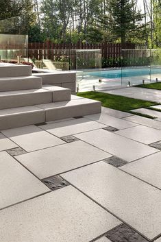 an outdoor patio with steps, grass and pool in the backround on a sunny day