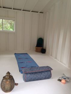 an empty room with a blue mat on the floor next to a teapot and other items