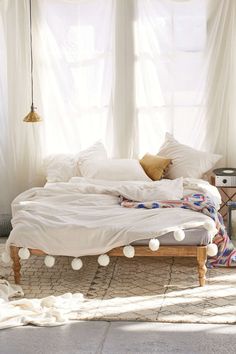 an unmade bed with white sheets and pom - poms