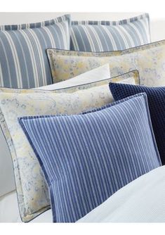 a bed with blue and white striped pillows on it's headboard, next to a pillow case