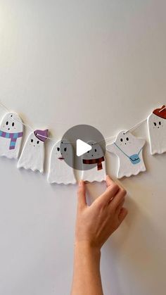 someone is making paper ghost garlands on the wall with their hands and thumbnails