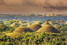 the chocolate hills are surrounded by trees and clouds