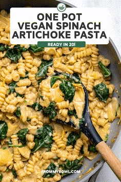 one pot vegan spinach artichoke pasta in a skillet with a wooden spoon