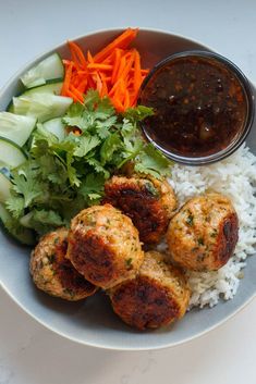 a white plate topped with meatballs, rice and veggies next to a bowl of sauce