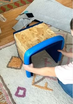 a child is playing with a wooden table on the floor in front of a rug