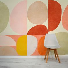 a white chair sitting in front of a wall painted with different colored circles on it