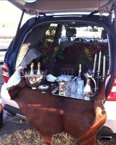 the back end of a car filled with bottles and silverware on top of hay