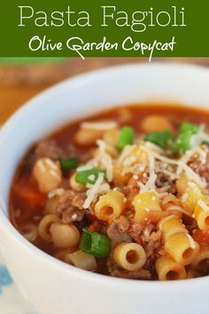 a white bowl filled with pasta and meat soup on top of a blue and white napkin