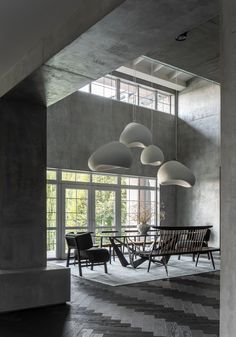 a room that has some chairs and tables in it with lights hanging from the ceiling