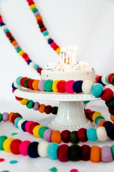 a birthday cake with white frosting surrounded by multicolored garlands and beads