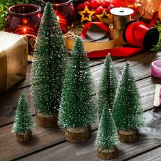 small christmas trees sitting on top of a wooden table next to candles and other decorations