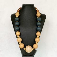 "This chunky boho necklace was hand beaded using a mix of large 25mm round distressed wooden beads in muted navy blue and warm tan, separated by a variety of unique wooden beads and gemstone rondelles.  The finishing touch?  An extra large 35mm round distressed beige wooden focal bead - a super stylish and unique look!  The necklace measures 28.5 inches in length and is securely fastened with a silver clasp.  Perfect for any gender!  Length can be adjusted if needed - just ask! Wood represents a Wooden Beads Necklaces For Jewelry Making, Round Wooden Beads Necklaces For Jewelry Making, Bohemian Round Brown Beads, Adjustable Rustic Wooden Beaded Necklaces, Rustic Adjustable Wooden Beaded Necklaces, Earthy Large Beads For Jewelry Making, Bohemian Brown Beaded Round Necklaces, Bohemian Brown Beaded Necklace, Earthy Wooden Beaded Necklaces