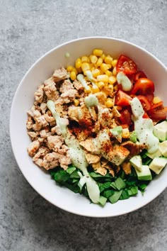 a white bowl filled with meat, vegetables and dressing