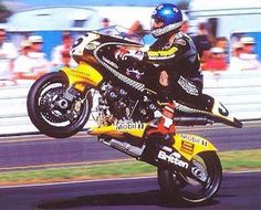 a man riding on the back of a yellow motorcycle down a race track with spectators in the background