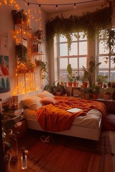 a bedroom with lots of plants in the window sill and an orange blanket on the bed