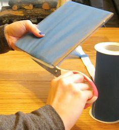 a woman is cutting up a piece of blue paper on a table with a pair of scissors