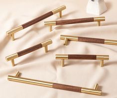 six brass and wood drawer pulls on a white sheet with gold trimmings in the shape of rectangles