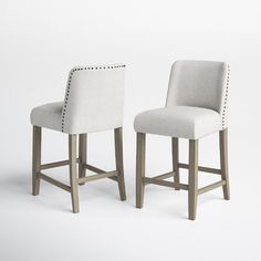 two white upholstered barstools with studding on the backrests