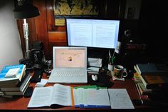 an open laptop computer sitting on top of a desk next to books and other items