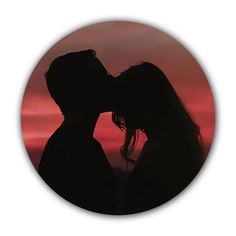 the silhouette of two people kissing in front of an orange and pink sky at sunset