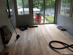 a room with hard wood flooring and a vacuum on the ground in front of an open door