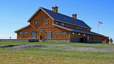 a large wooden building sitting on top of a lush green field next to an american flag