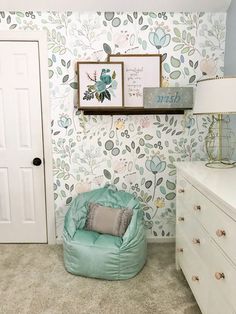 a room with a chair, dresser and wallpaper on the walls in it's corner