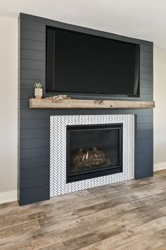 a fireplace with a flat screen tv above it and wood flooring on the other side