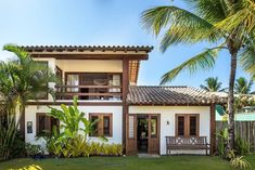 a white house with brown shutters and palm trees