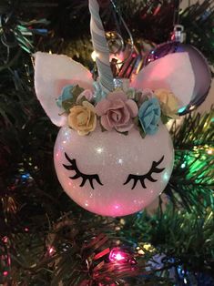 an ornament shaped like a unicorn's head with flowers on it, hanging from a christmas tree